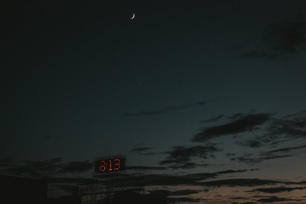 a full moon is seen in the sky above a clock